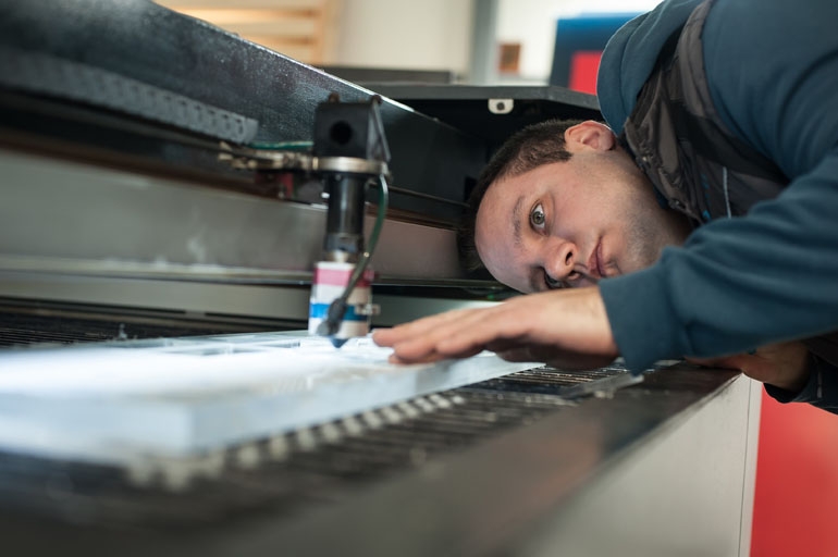 photograph showing service technicians during repair, service of laser cutting machine